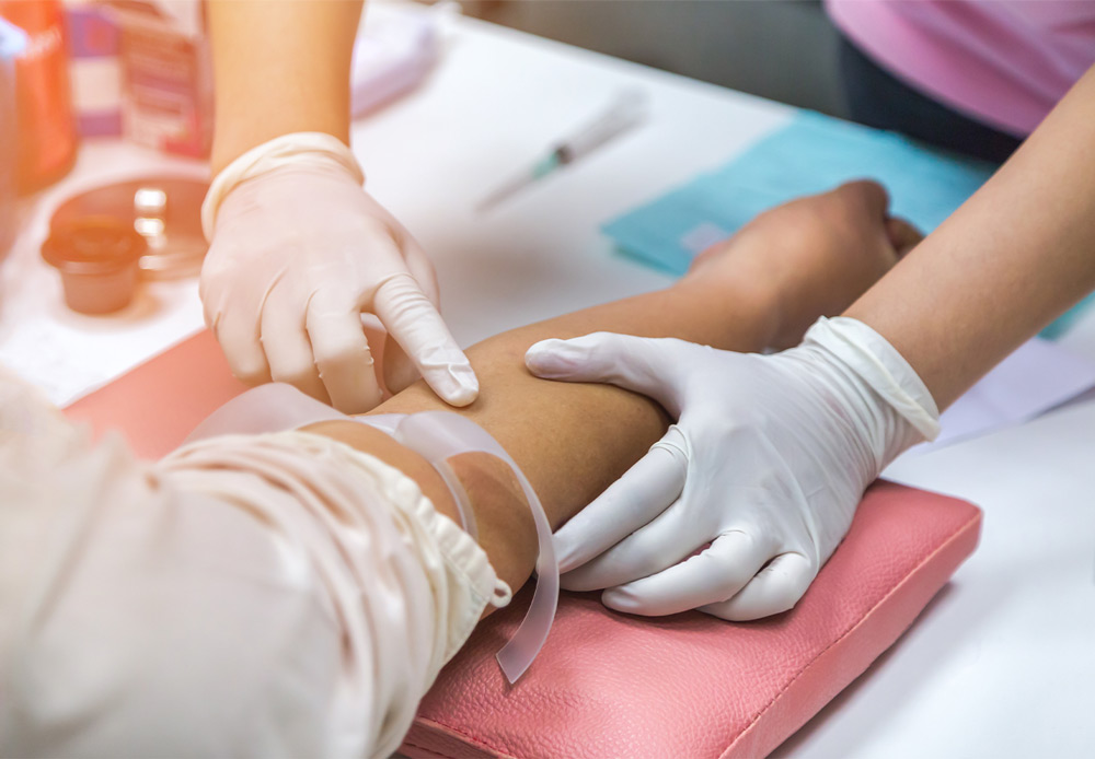 medical technician probing a person's arm for a vein before drawing blood