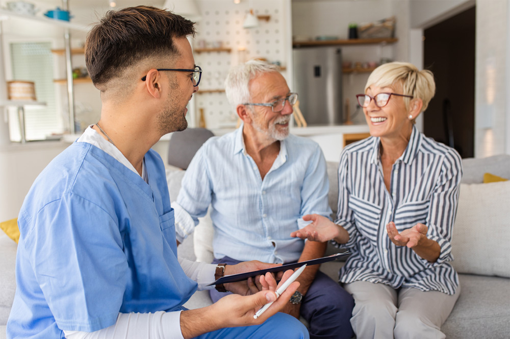 Medical technician consulting with a senior couple at their home