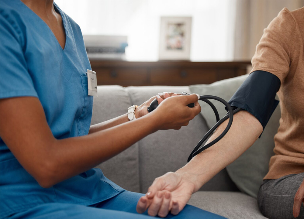 Closeup of a medical technician taking a patient's blood pressure reading in their home